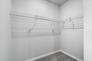 the closet of a studio apartment with white walls and hanging racks